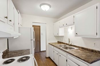 A kitchen with white cabinets and a stove top oven.