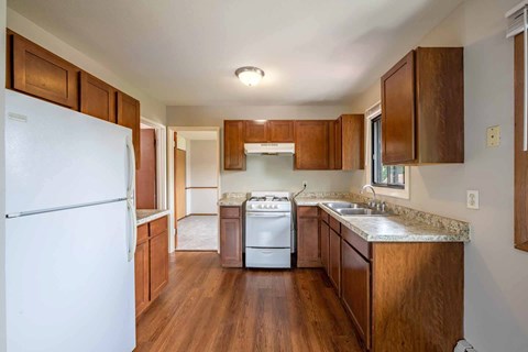 A kitchen with wooden cabinets and a white fridge.