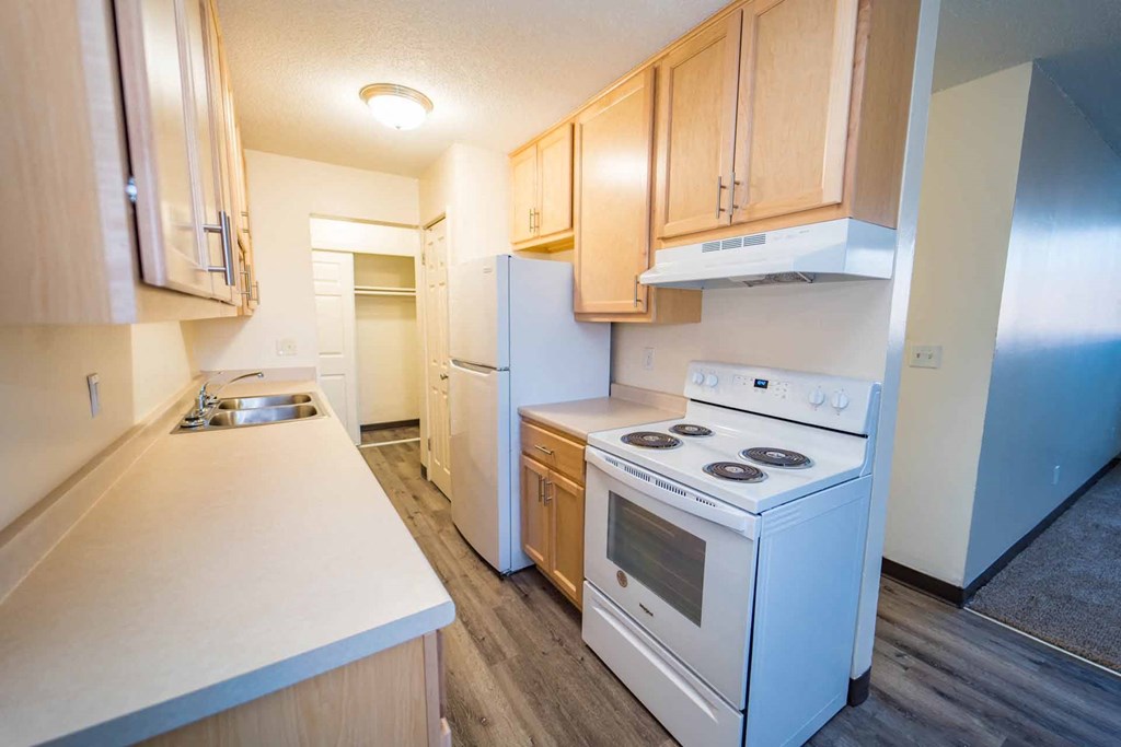 A kitchen with white appliances and wooden cabinets.