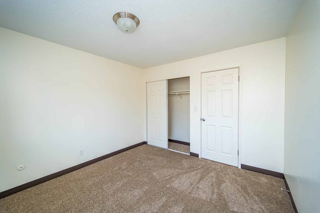 A room with a carpeted floor and two doors.