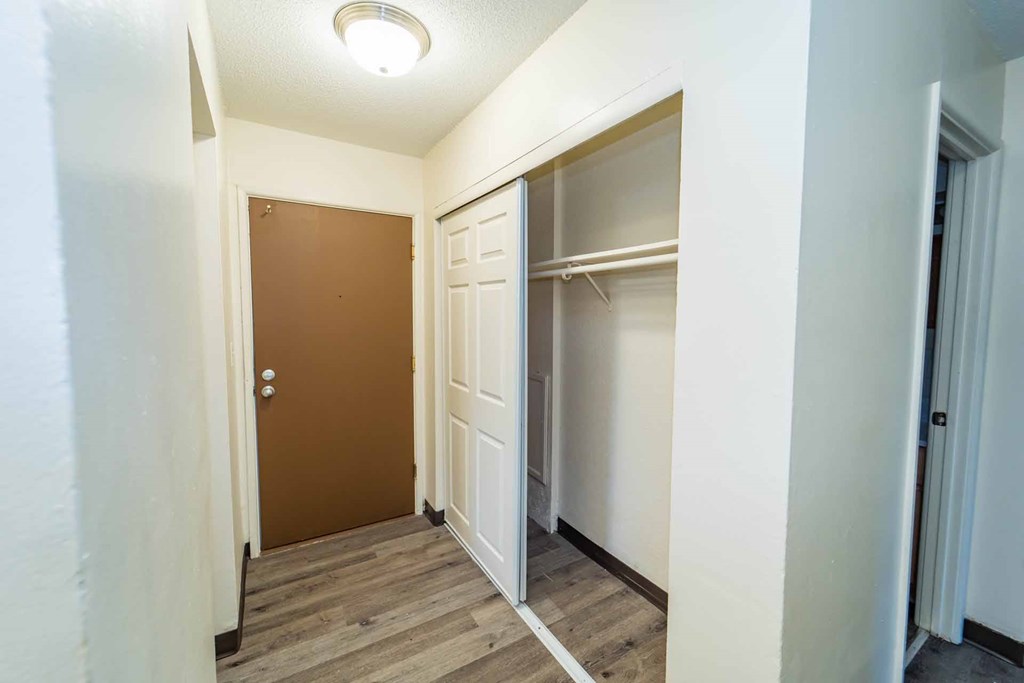 A hallway with a brown door and white walls.