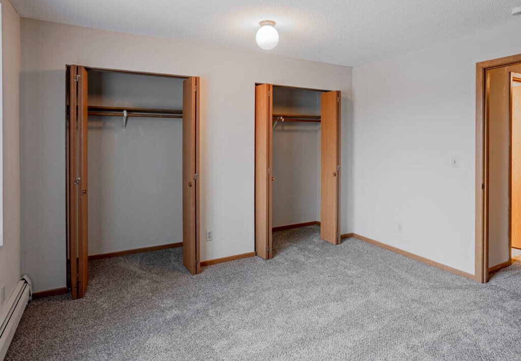 a bedroom with three closets and a carpeted floor