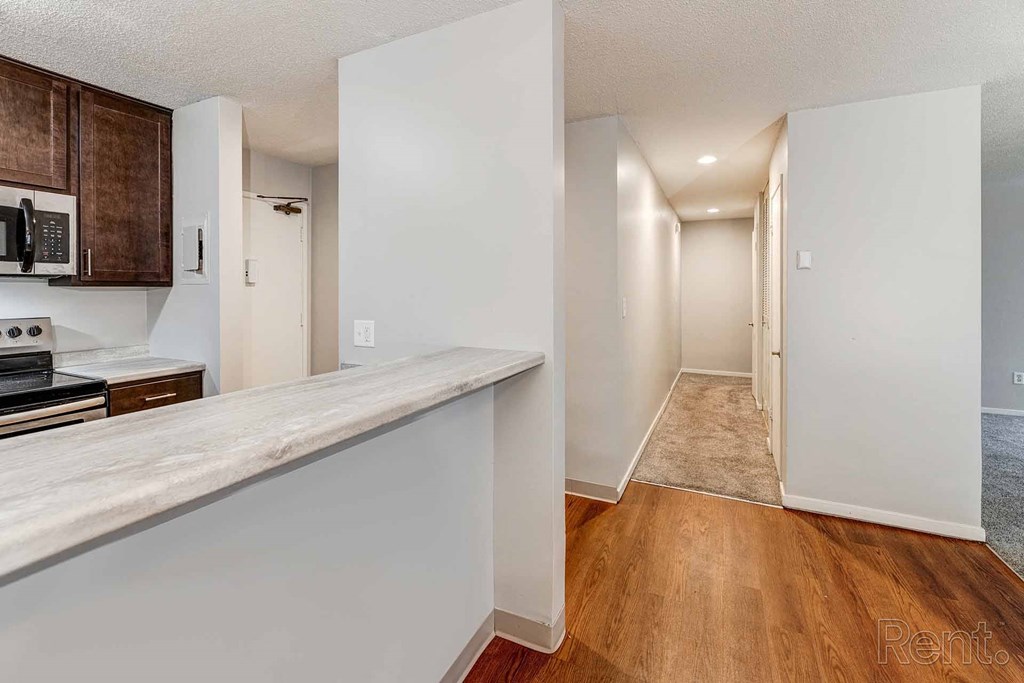 a kitchen with a counter and a hallway to a living room