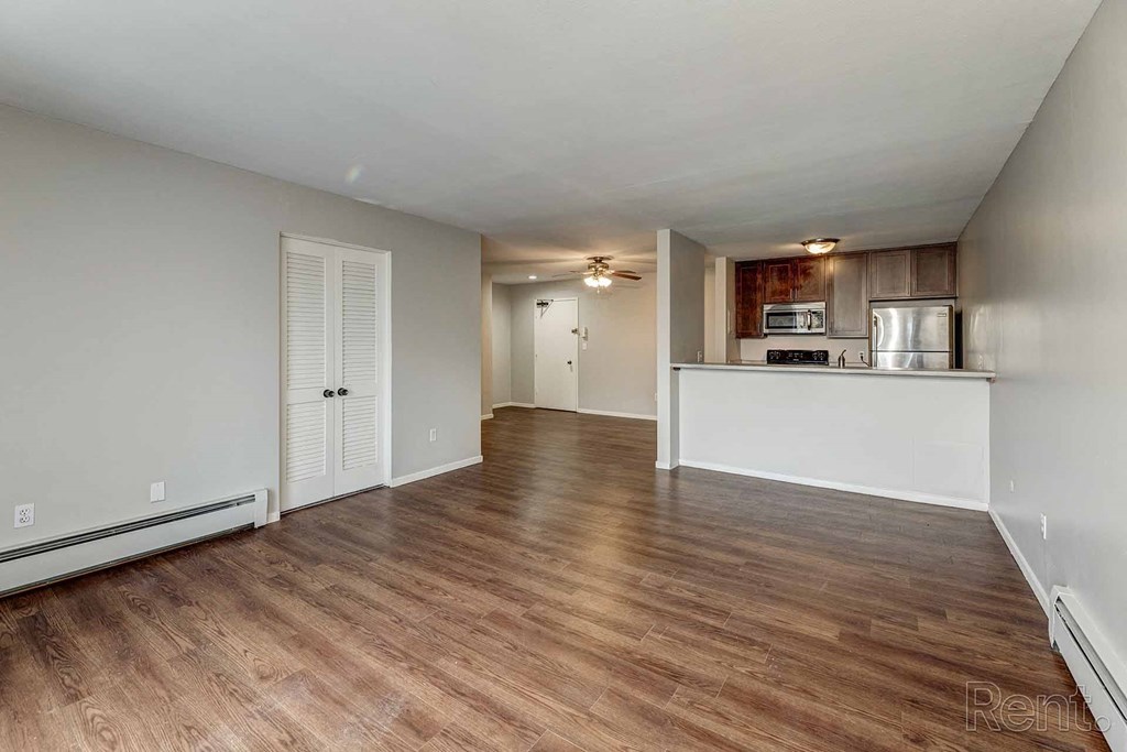 an empty living room and kitchen with wood flooring