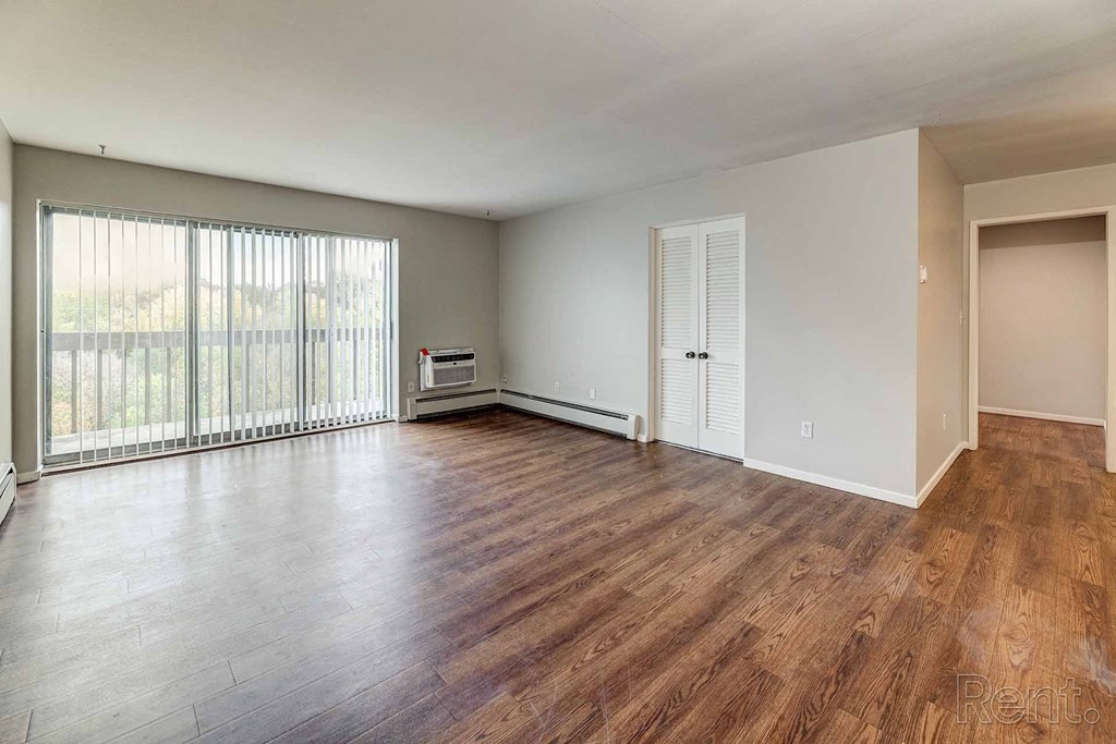 an empty living room with wood floors and a large window