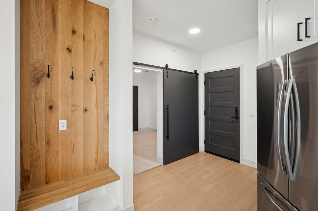 a kitchen with a wooden door and a stainless steel refrigerator