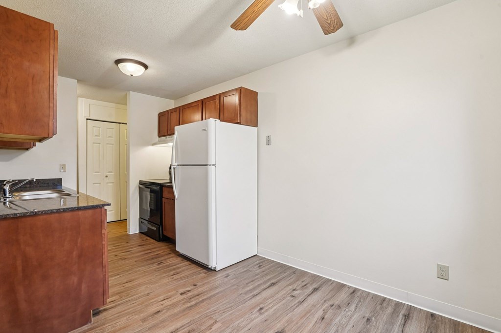 A kitchen with a white refrigerator and wooden cabinets.