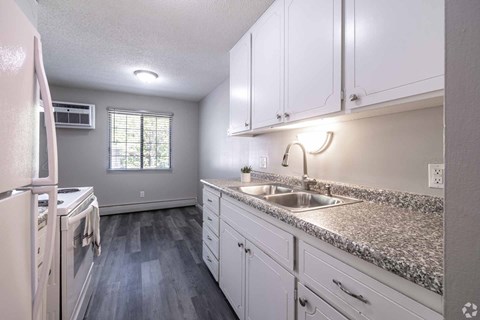 A kitchen with white cabinets and a granite countertop.