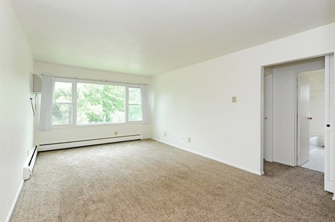 an empty living room with a large window and white walls