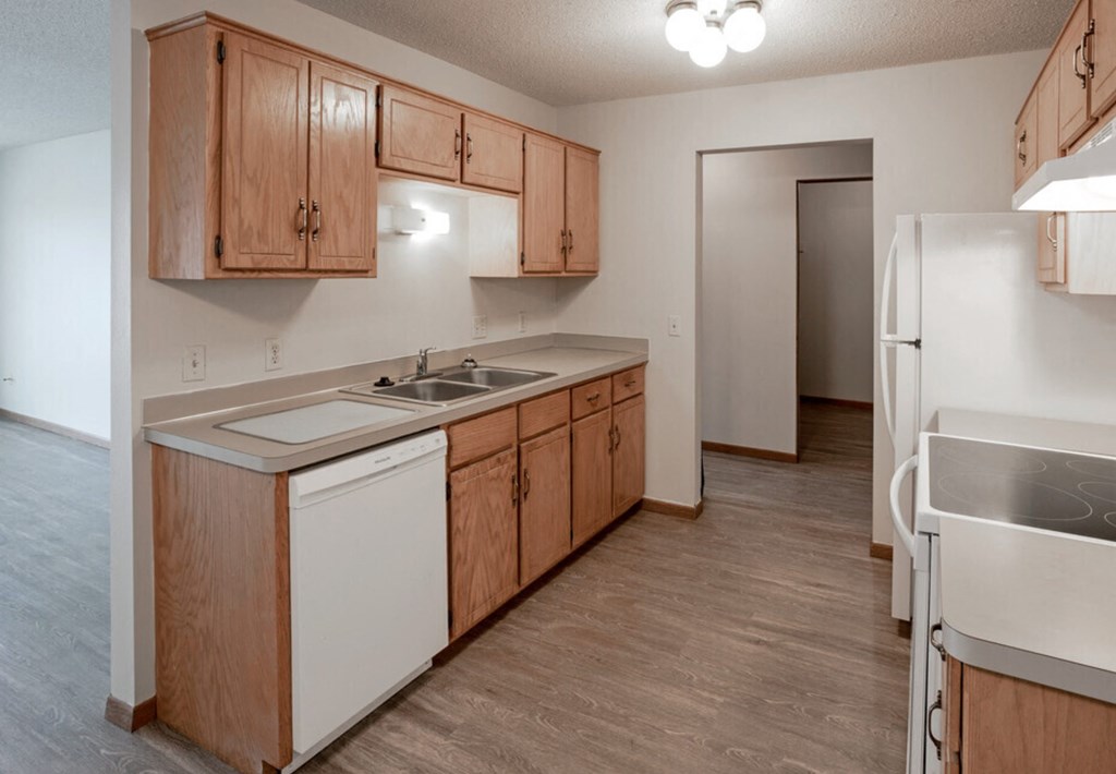 an empty kitchen with wooden cabinets and white appliances