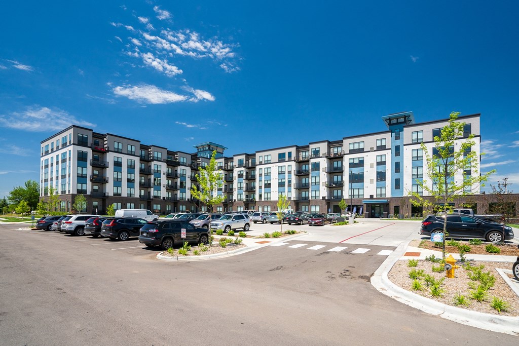 an empty parking lot with cars in front of an apartment building