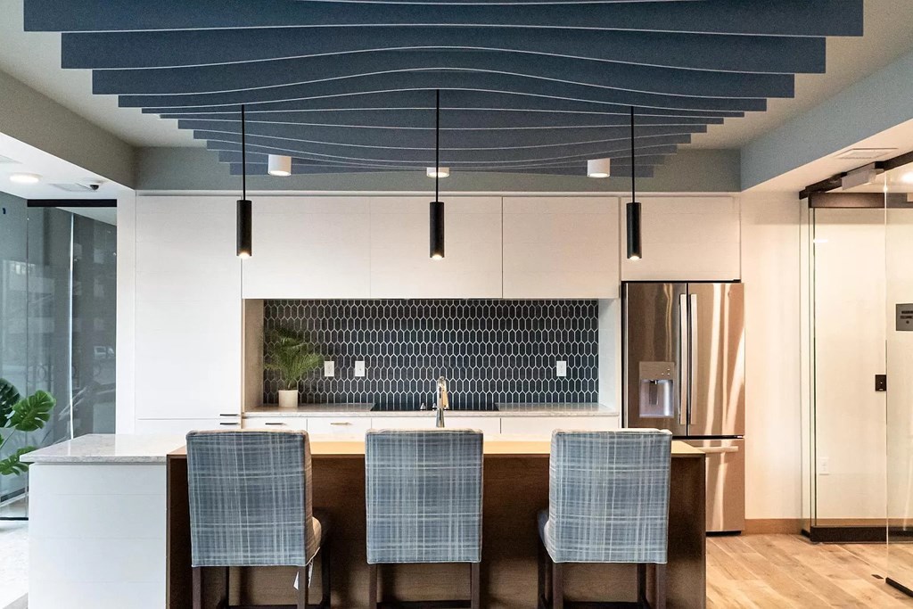 a kitchen with white cabinets and a island with three chairs