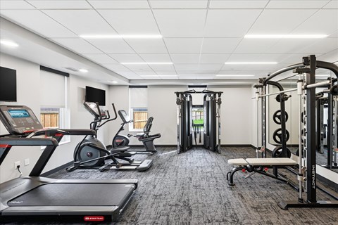 A gym with treadmills, elliptical machines, and weightlifting equipment.