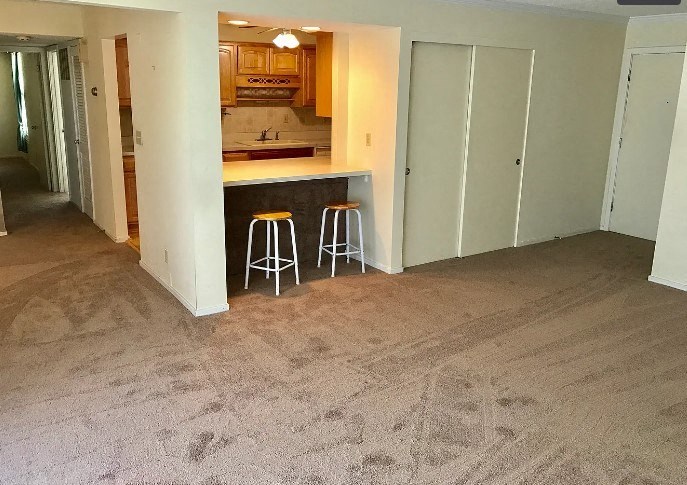 a living room with two stools and a kitchen in the background