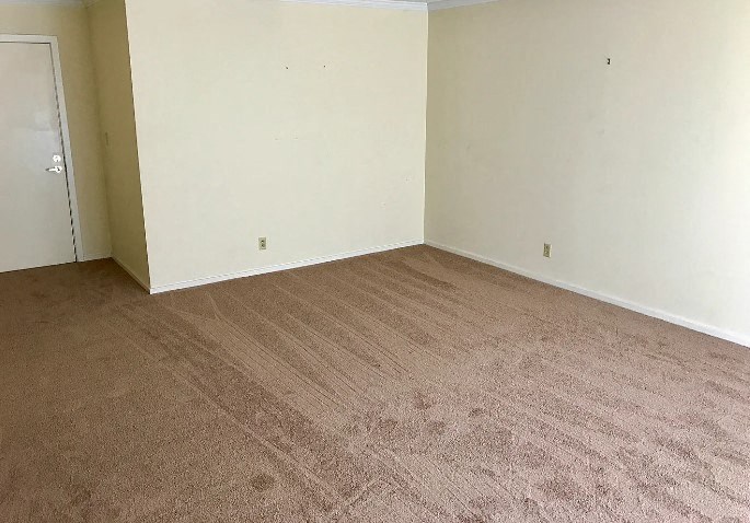 an empty room with a white wall and carpet