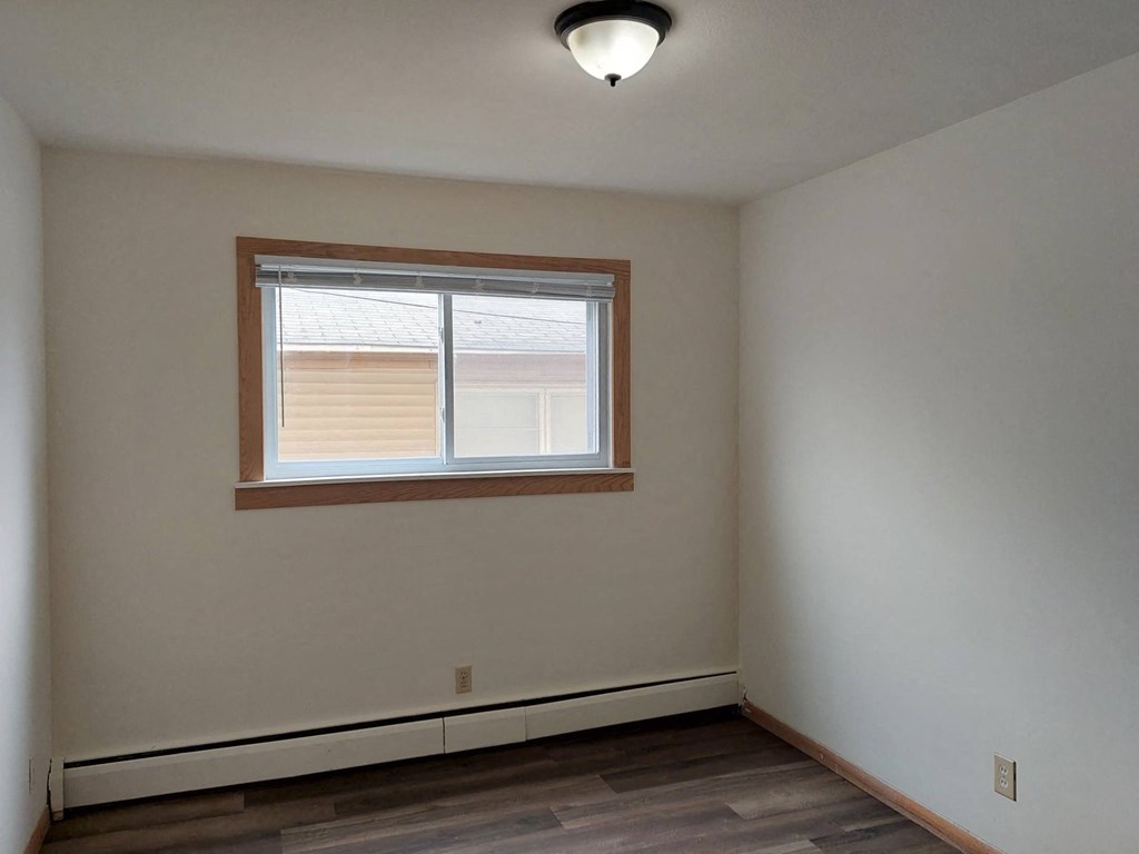 a bedroom with a window and a hard wood floor