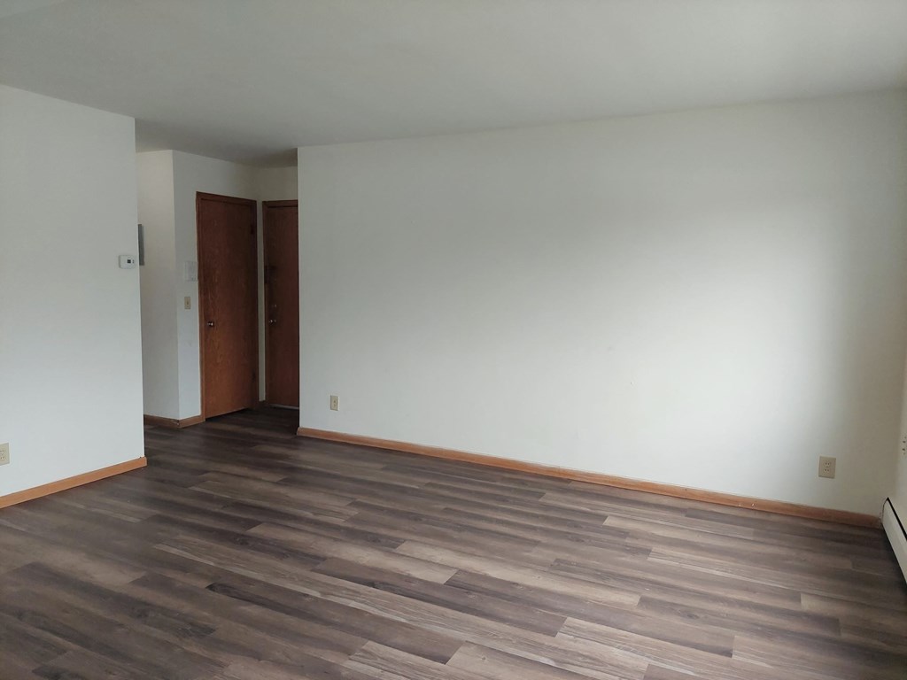 an empty living room with wood floors and white walls
