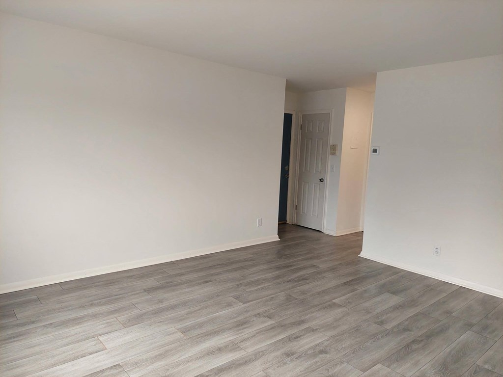 a empty room with white walls and wood flooring