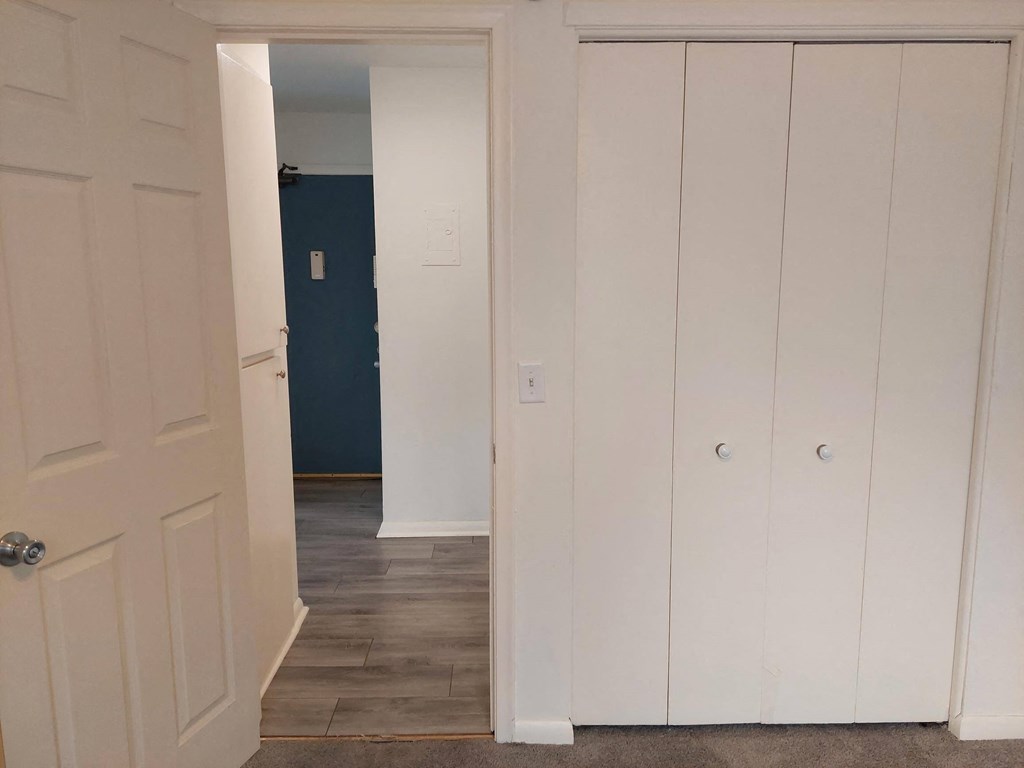 a hallway with white closets and a door to a blue room