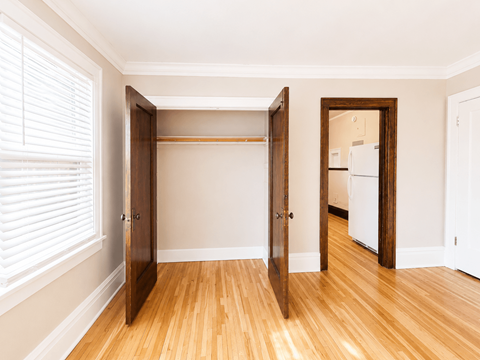 A room with a white wall and a wooden floor with a closet.