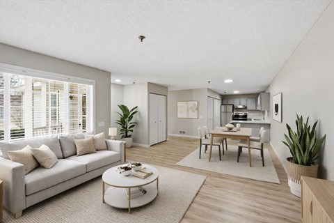 A modern living room with a grey sofa, a coffee table, and a dining table set up.