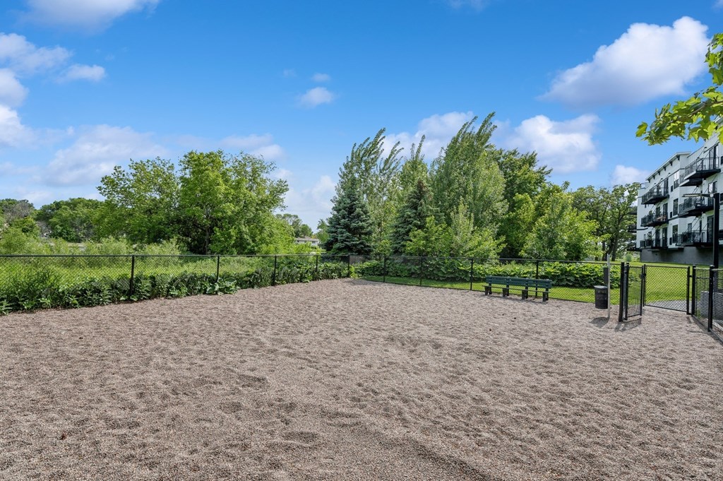 a dirt area with benches and trees in a park