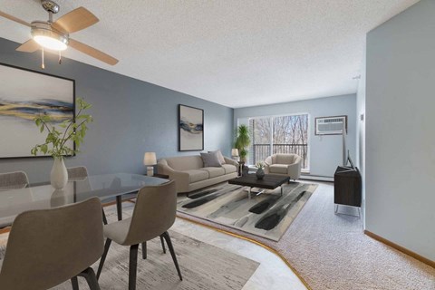A living room with a glass table and grey chairs.