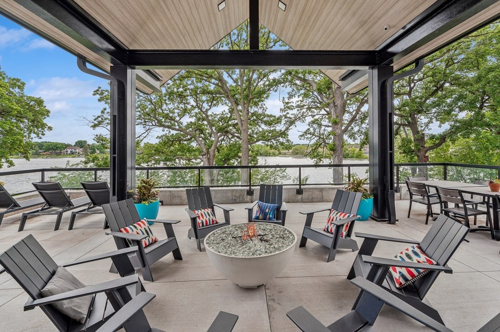 a patio with chairs and tables and a fire pit