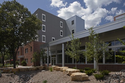 A modern building with a grey facade and a landscaped area in front.