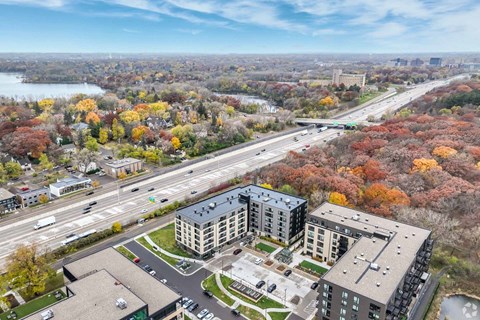 A large apartment complex is surrounded by trees with autumn leaves.