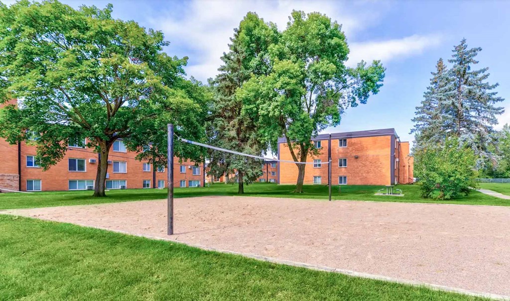 A volleyball net stands in the middle of a sandy court.