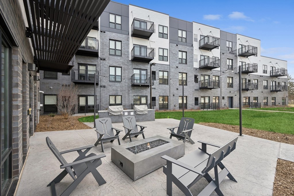 Wangstad Commons, Brooklyn Center, modern outdoor seating area with a fire pit in front of a residential building.