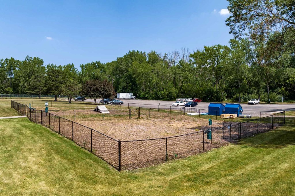 A baseball field with a fence and a blue building in the background.