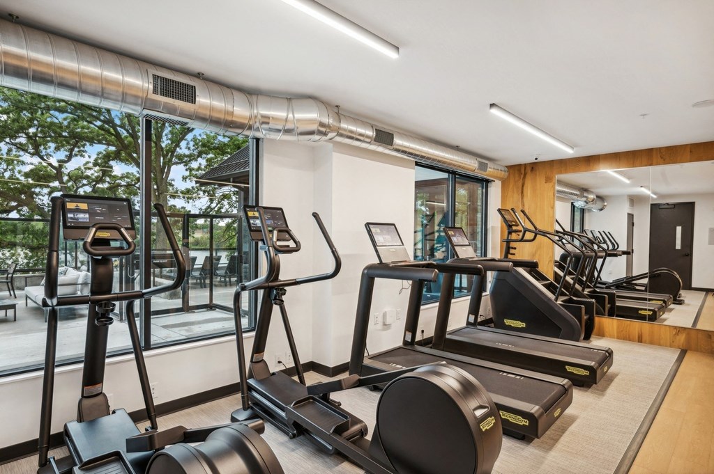 a gym with treadmills and other equipment in a room with a large window