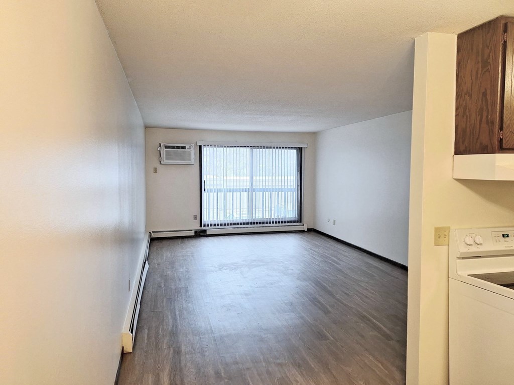 an empty kitchen and living room with wood flooring and a window