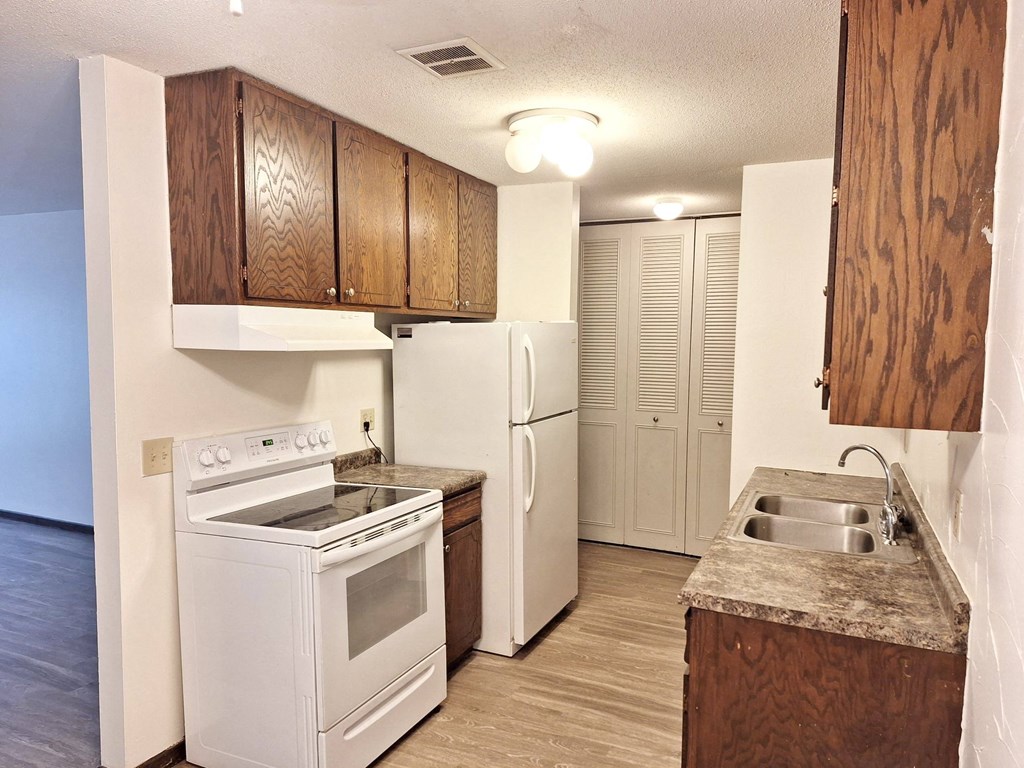 an empty kitchen with a stove refrigerator and sink