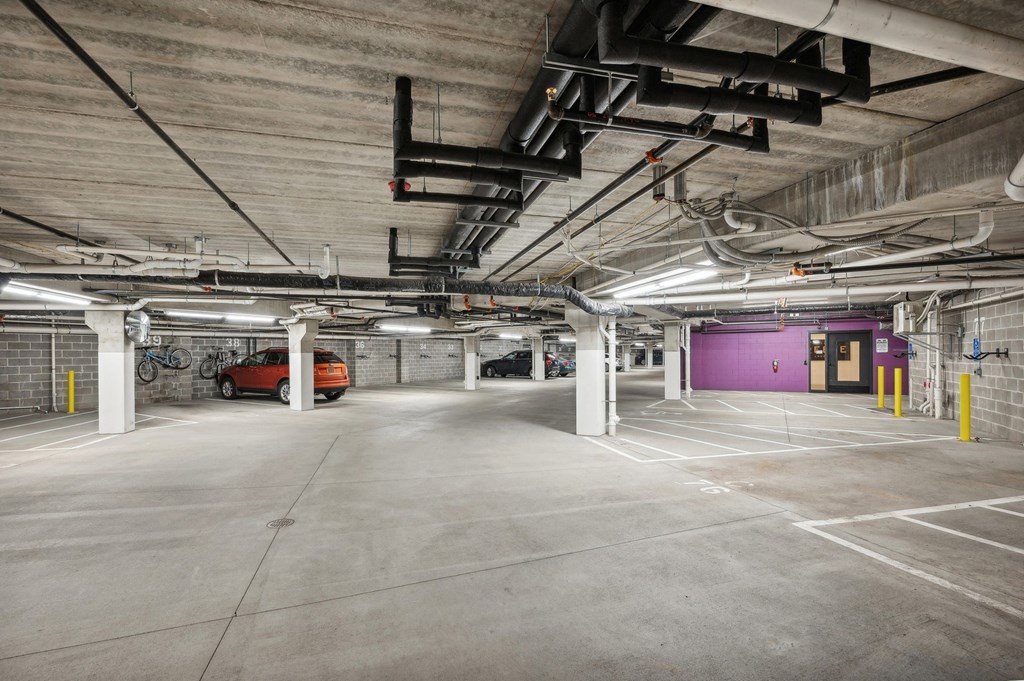 a large parking garage with a purple door and pipes hanging from the ceiling