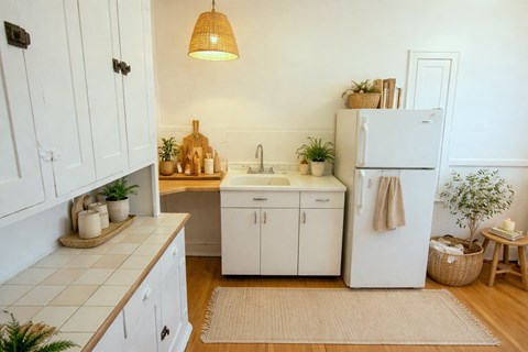 A kitchen with white cabinets and a white fridge.