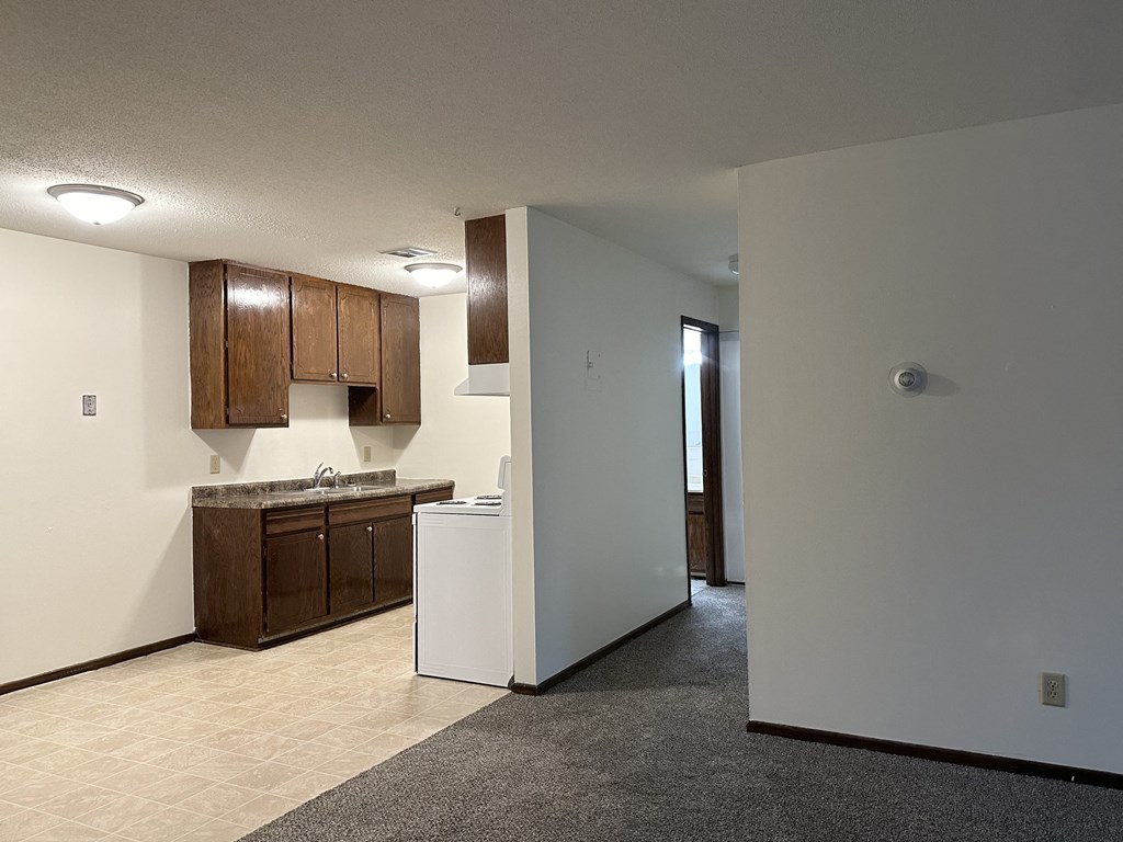 an empty kitchen with brown cabinets and white walls