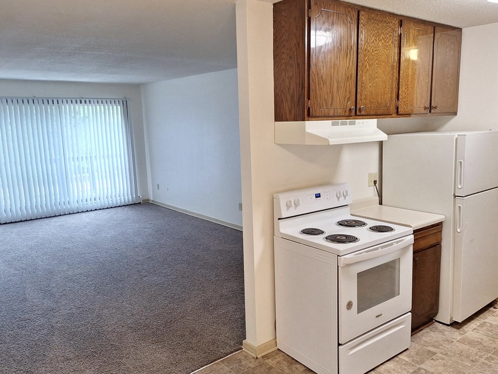 an empty kitchen with a white stove and refrigerator