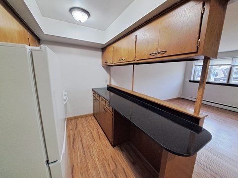 A kitchen with wooden cabinets and a black countertop.