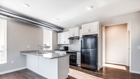 a kitchen with white cabinets and a black refrigerator