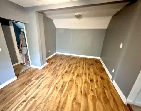 a living room with a hard wood floor and gray walls