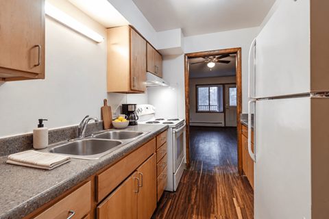A kitchen with wooden cabinets and a white fridge.