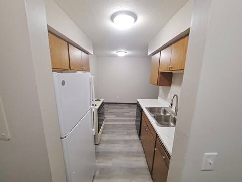 A kitchen with a white refrigerator and wooden cabinets.