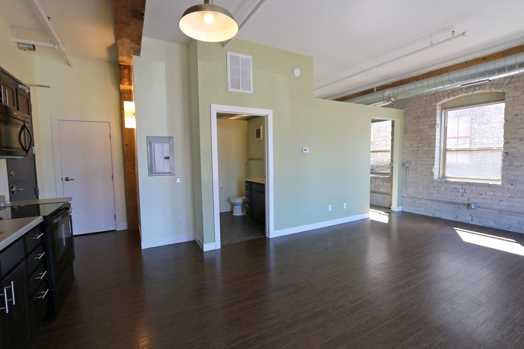 an empty living room with wood floors and a brick wall