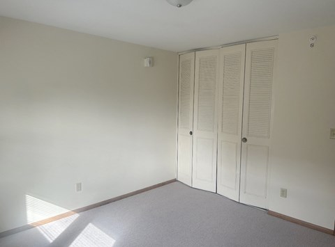 a bedroom with white walls and two closet doors