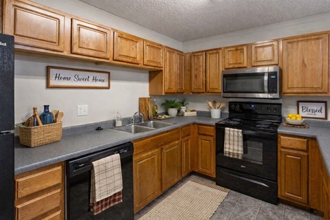 A kitchen with wooden cabinets and a sign that says "Home Sweet Home.".