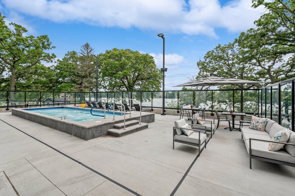a pool and patio with chairs and umbrellas on a rooftop
