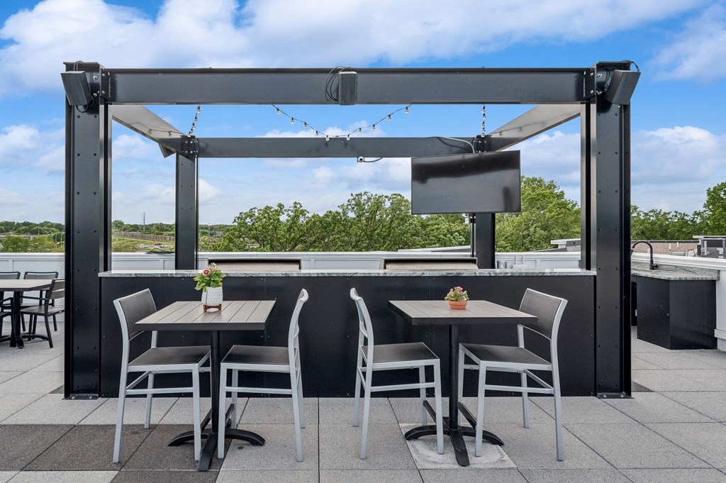 a rooftop patio with tables and chairs and a tv